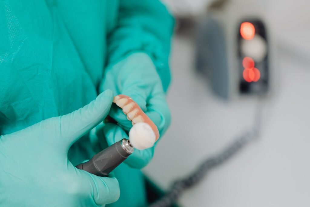 Dental technician in gloves polishing a denture with a rotary handpiece