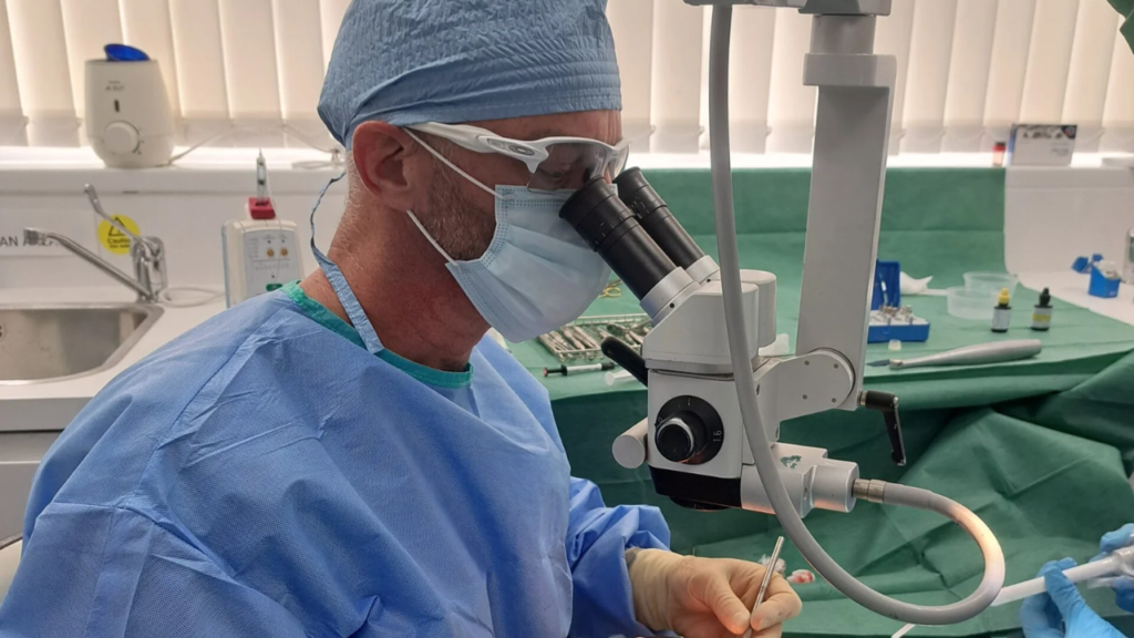 Dr Andrew Fennell working with a surgical microscope in the treatment room at Love Implants, Colchester.